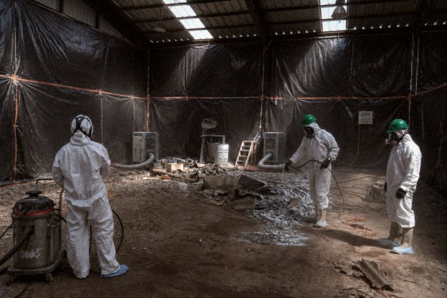 Cuadrilla con EPP completo trabajando en área confinada durante retiro de asbesto friable